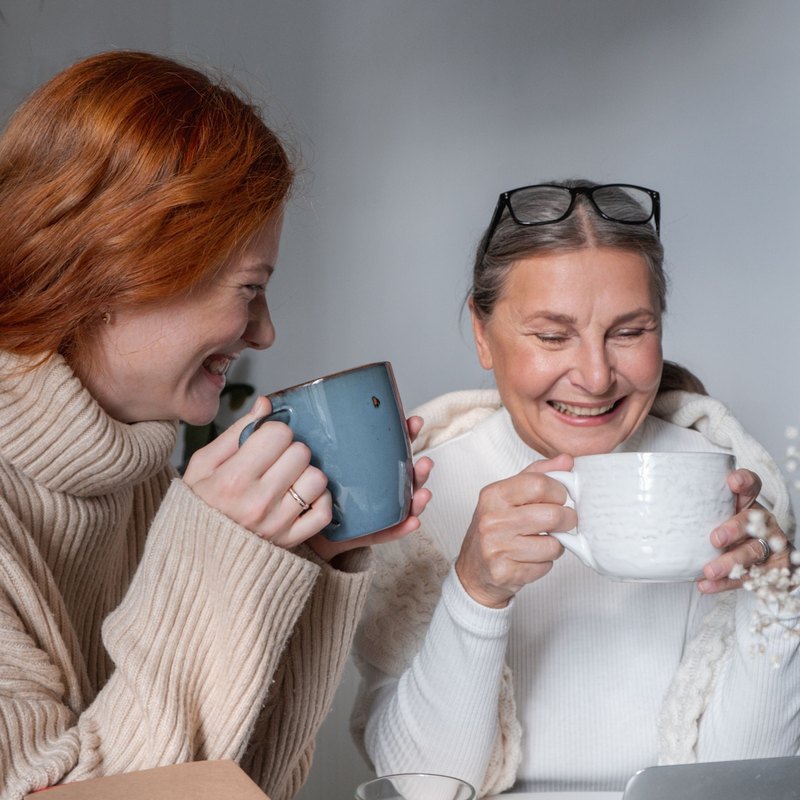 Two women laughing together over coffee at a table